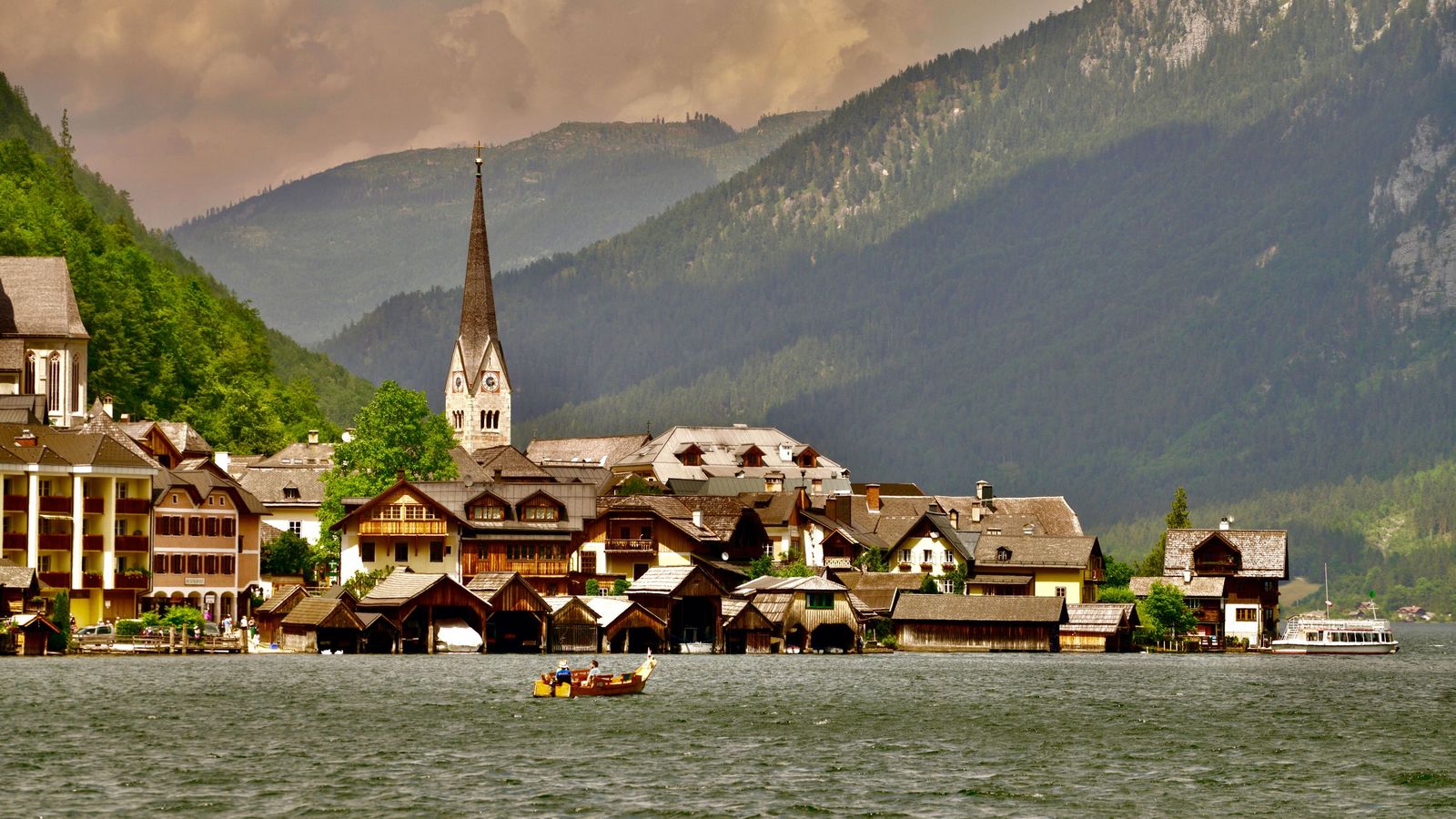 Hallstatt church and lakeside houses below the mountains in warm evening light