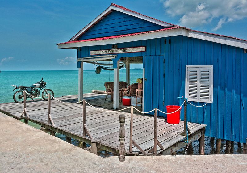 A blue wooden beach house on a jetty over the sea