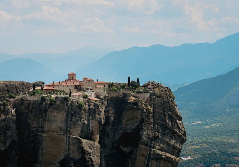 A monastery on a flat-topped rock above a green valley