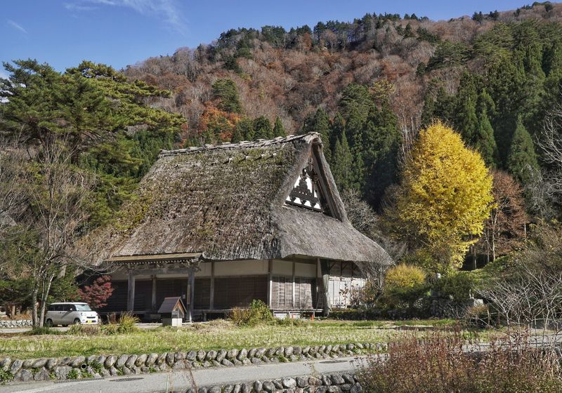 A single thatched farmhouse surrounded by autumn trees