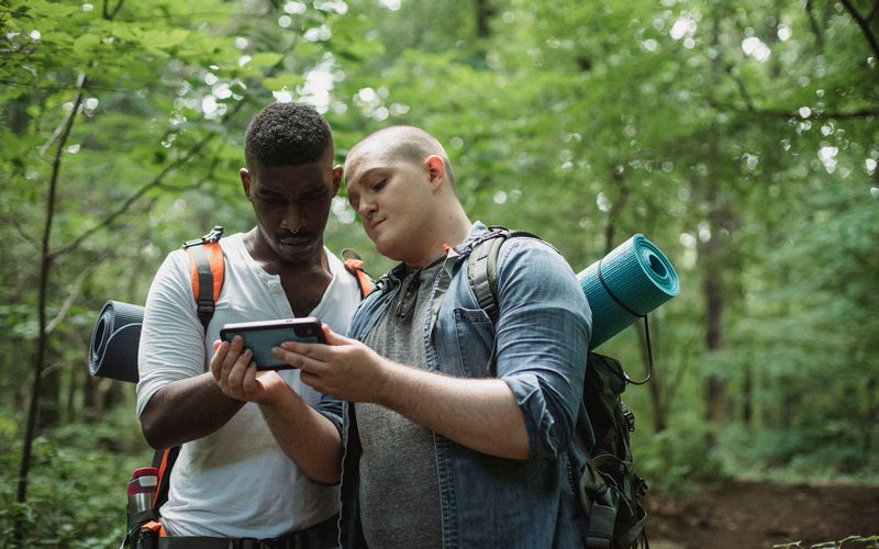 Two backpackers checking a map on a phone in the forest
